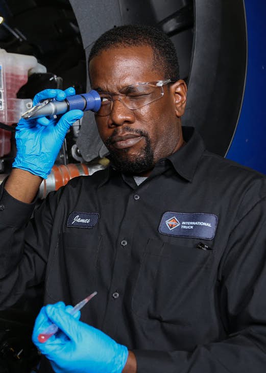 A person wearing gloves holding a tool to his eye