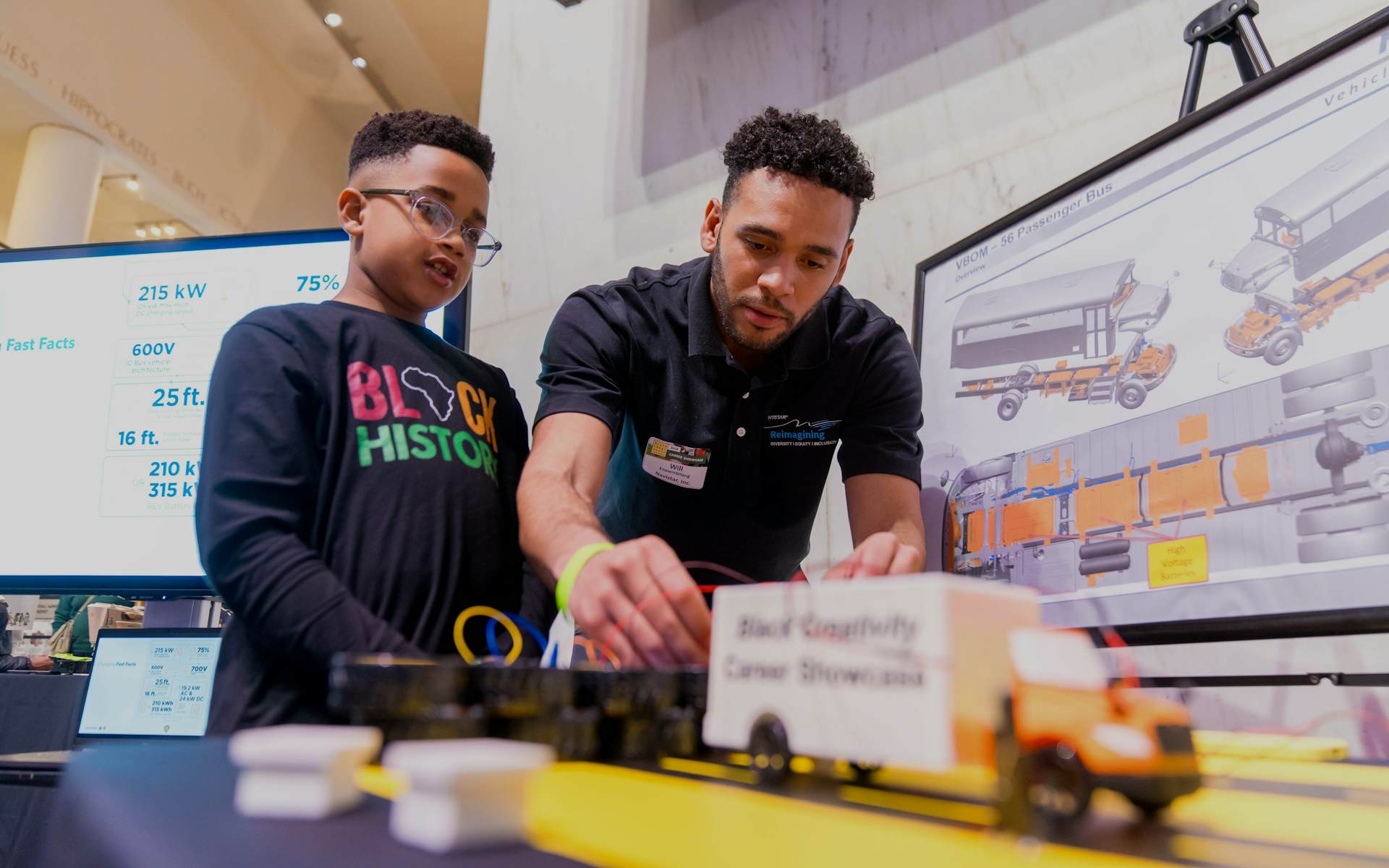 A child and an adult looking at a miniature truck.